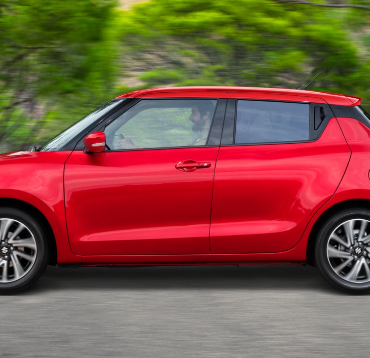 Side view of Suzuki Swift driving showing its compact hatch shape