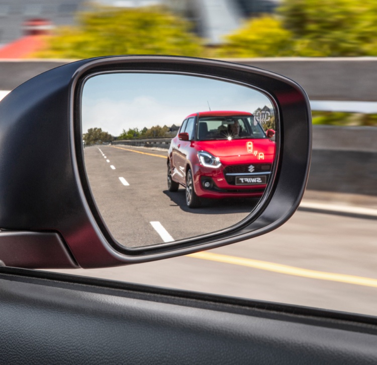Suzuki Swift wing mirror with blind spot monitor warning light illuminated and showing a reflection of Suzuki Swift