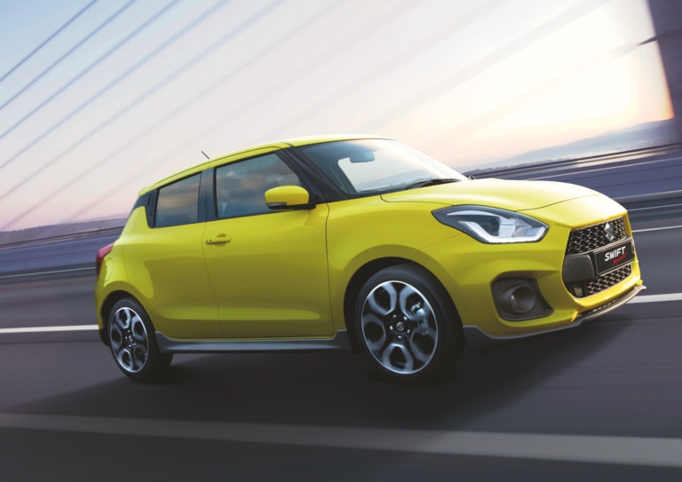 Yellow Swift Sport driving allow the road with sunset