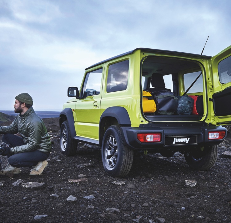 Jimny off road in rocky landscape with photographer, open boot packed with gear